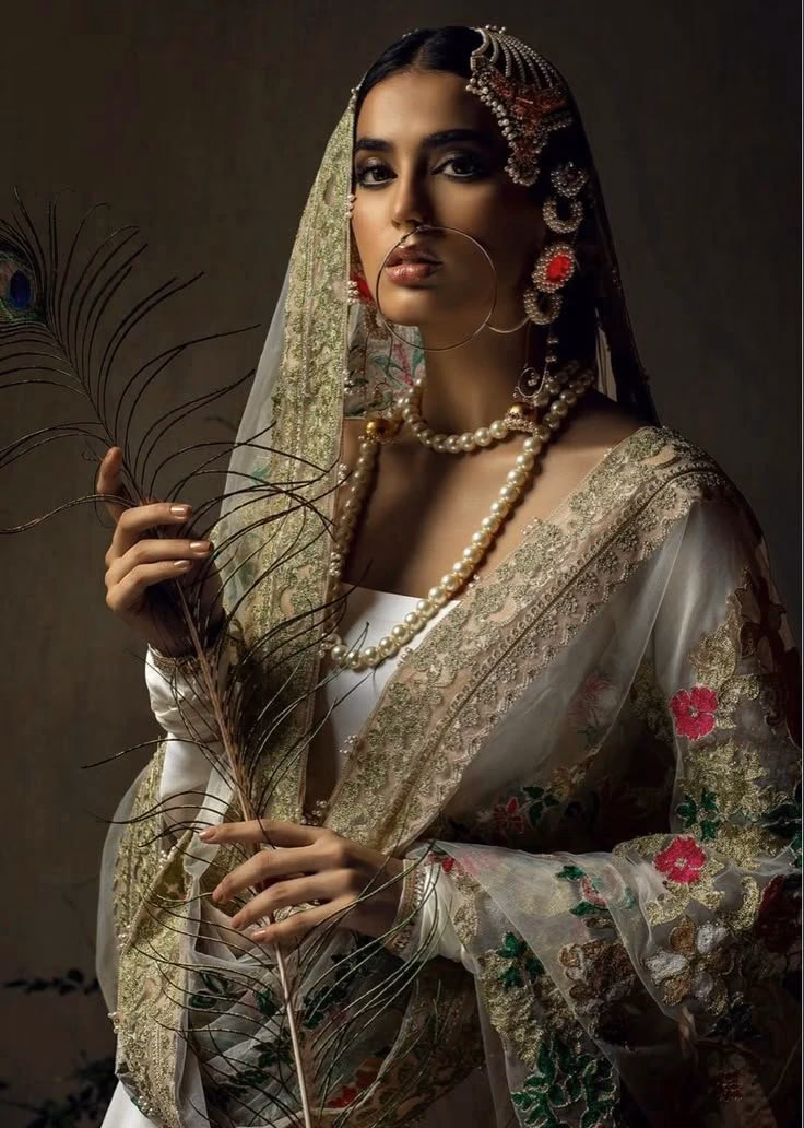 Bride in a white zari saree with gold embroidery and pearl jewelry
